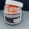 Jar of orange wellness gummies labeled Neighborhood Fiber Co. on a gray surface.