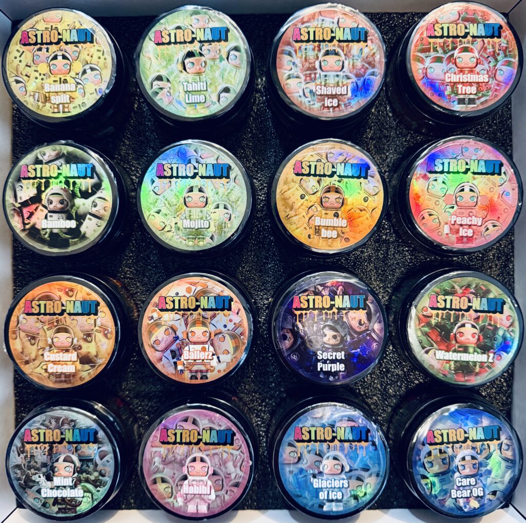 Colorful ASTRO-NAUT ice cream containers with unique flavors arranged in a neat grid on a black background.